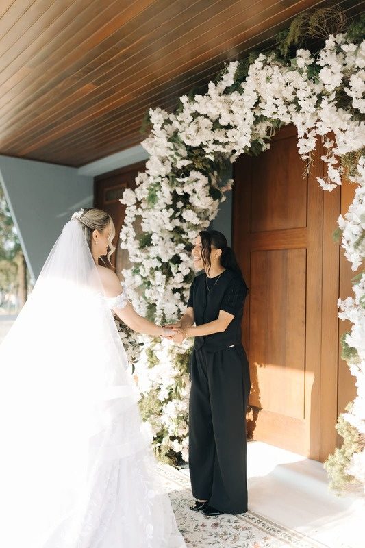 Assessora recebendo a noiva sob o arco de flores